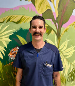 Picture of staff member smiling in front of jungle mural
